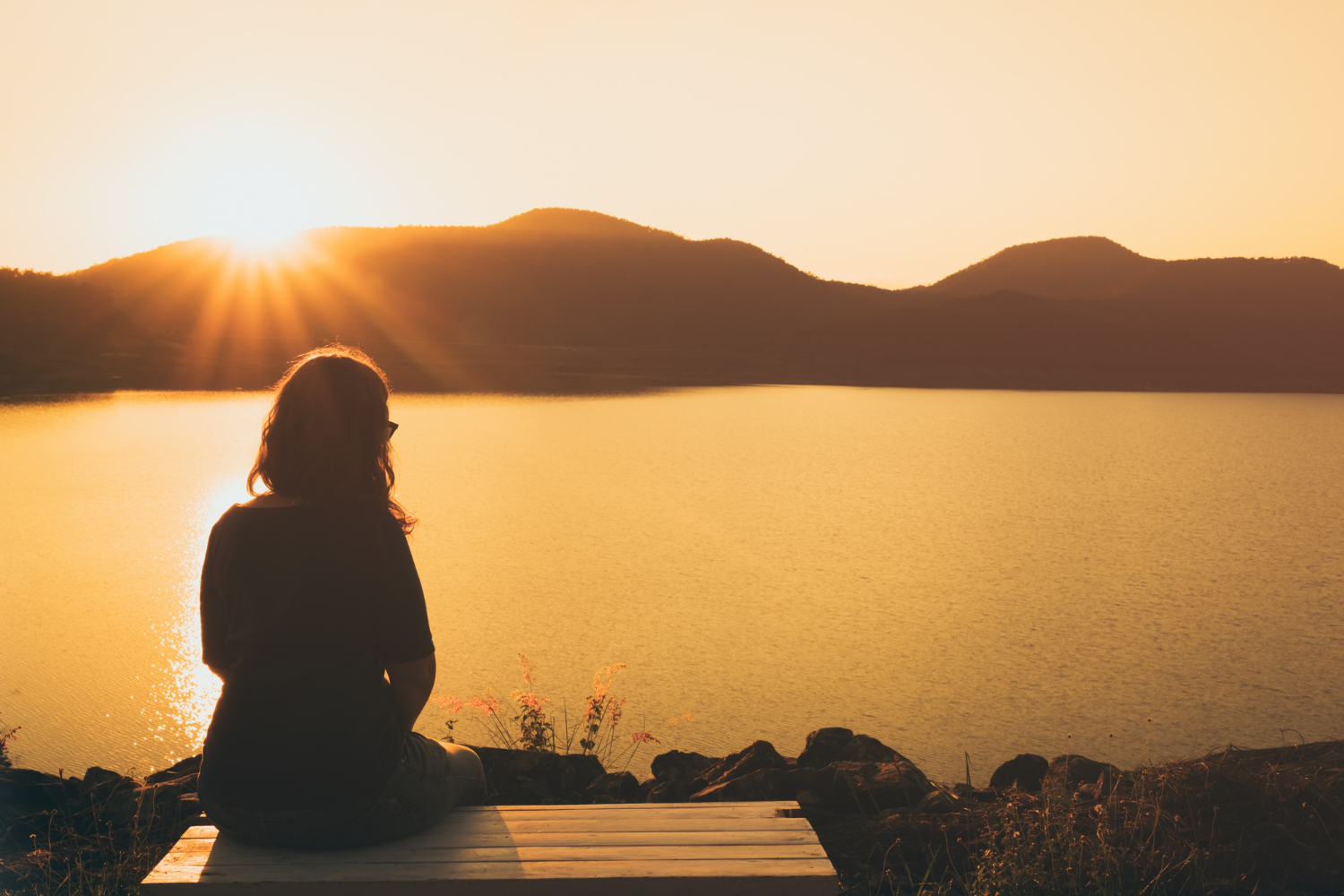 a woman sitting alone watching the sunset