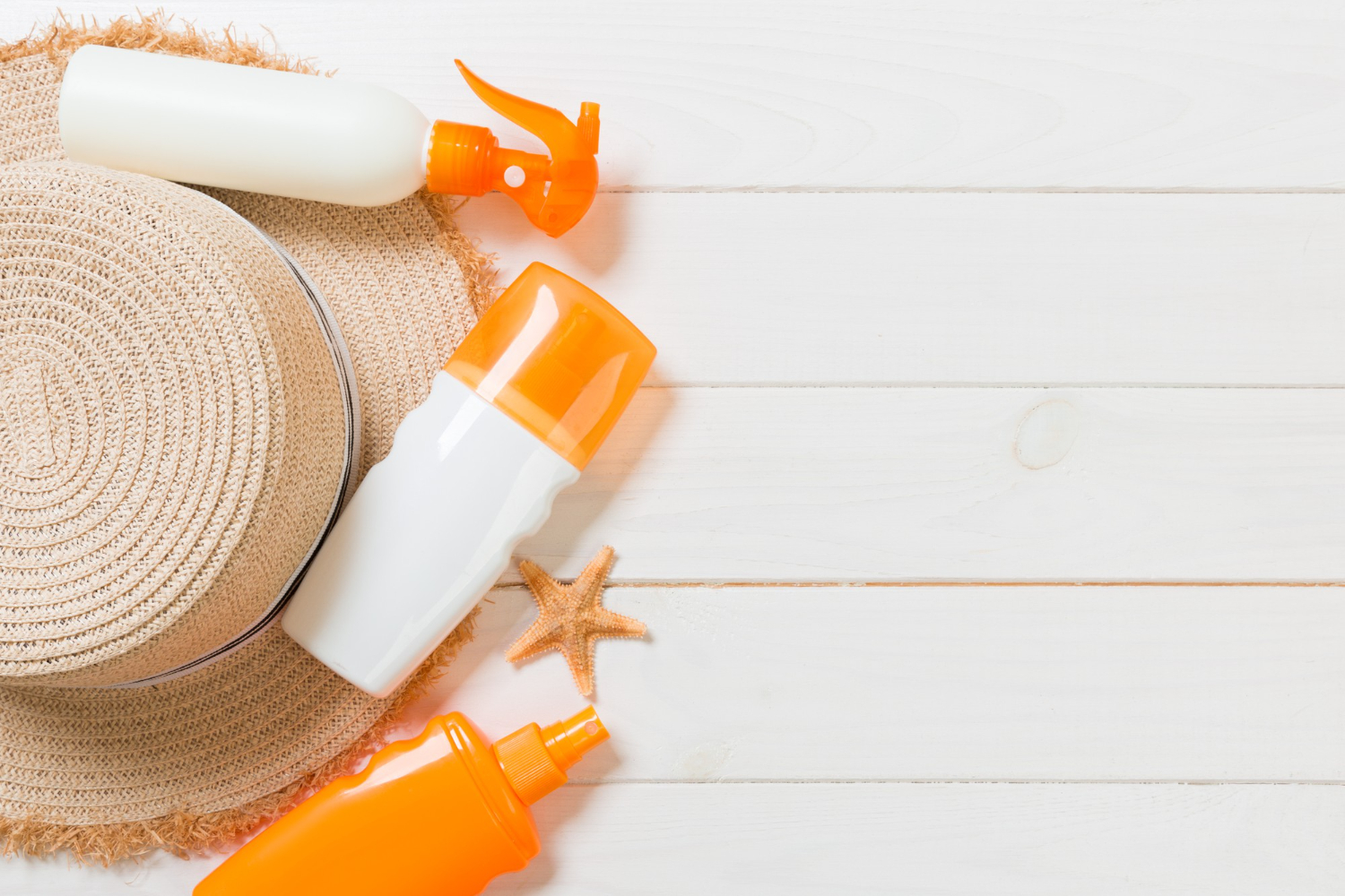 sunscreen bottles with starfish sunhat white wooden table with copy space travel healthcare accessories top view
